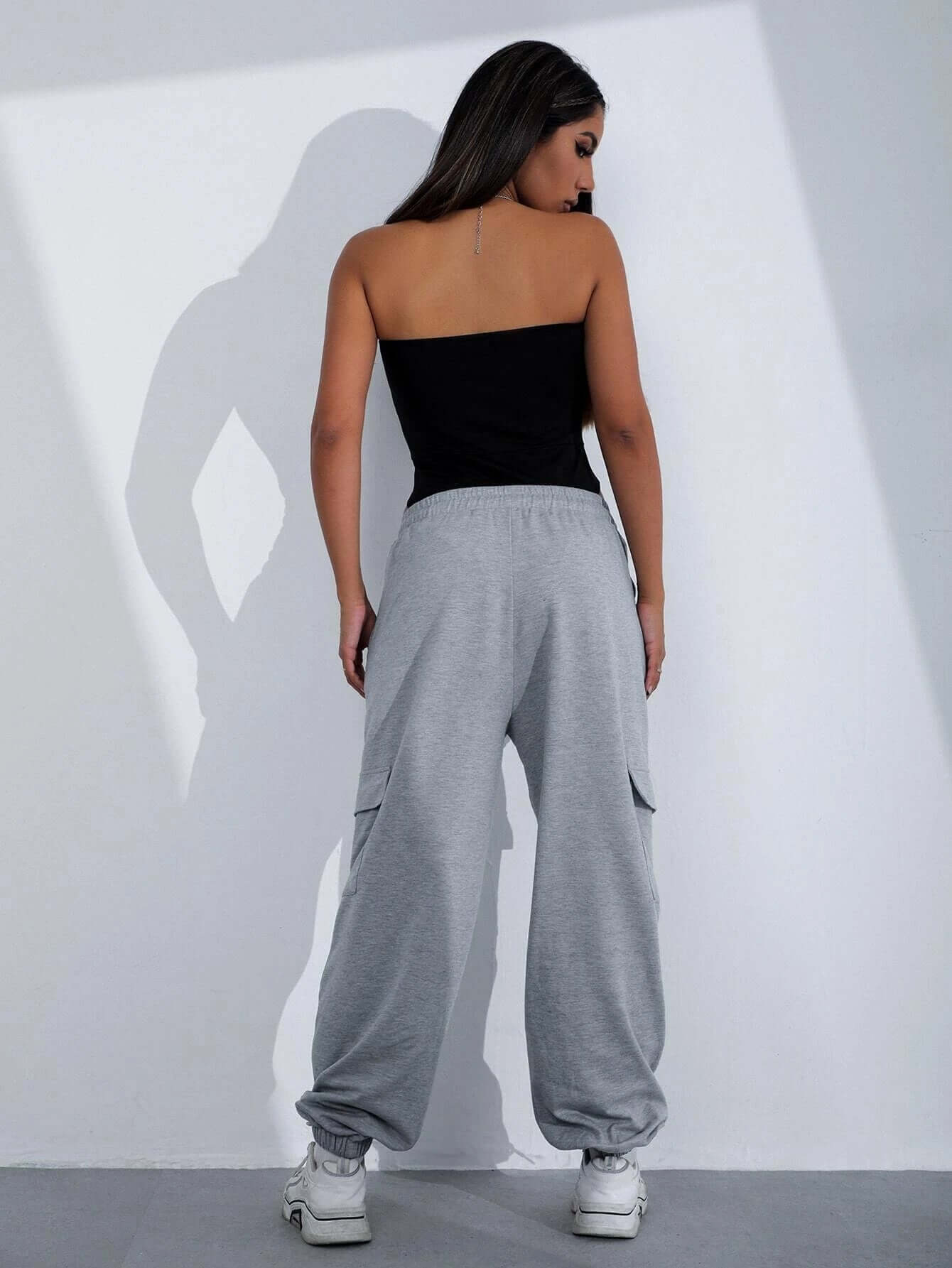 Woman wearing Sexy V-Chest One-Piece Tops Women Tight Bottoming Shirt Slim Slimming Onesies with grey baggy pants.